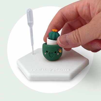A hand sets the Cactus Pal into the Acorny pot on its magnetic coaster