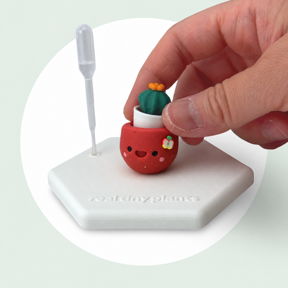 A hand sets the Cactus Pal into the Apple Cider pot on its magnetic coaster