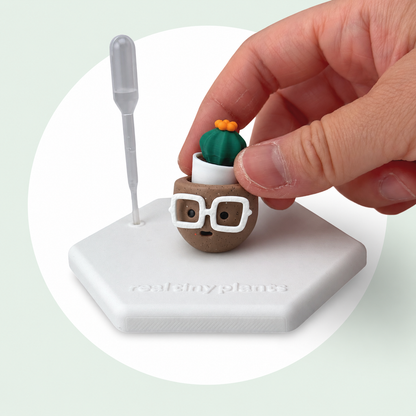A hand sets the Cactus Pal into the Hot Cocoa pot on its magnetic coaster