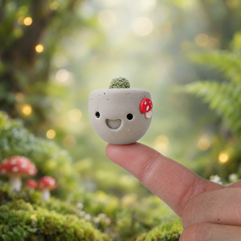 Mushroom Munchkin mini cactus pot on a fingertip in a mossy forest with red mushrooms